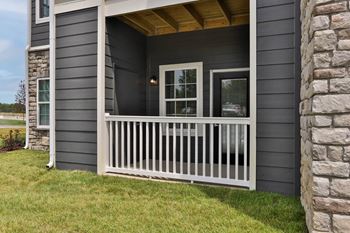 a porch of a house with a white railing and a stone wall  at Aventura at Hawk Ridge, Missouri